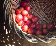 a wicker basket filled with apples on top of a wooden table