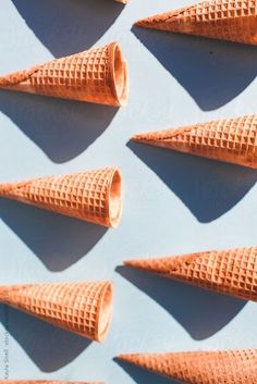 six cones of ice cream lined up against a white background by luke paddock for stocksy