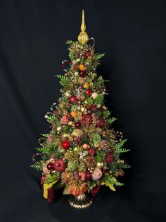 a small christmas tree with ornaments on it's sides and gold trimmings