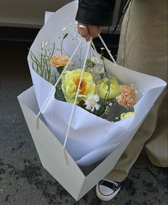 a person holding a paper bag with flowers in it