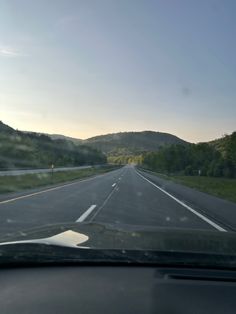 the view from inside a car looking down an empty road with mountains in the distance