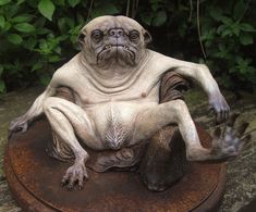 a statue of a dog sitting on top of a wooden table next to green plants