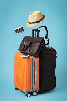 an orange suitcase, hat and camera on blue background