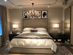 a bedroom with a large bed, chandelier and two lamps on the nightstands