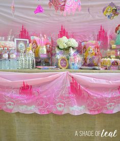 the table is covered with pink and white items for princess birthday party decorations, such as candy