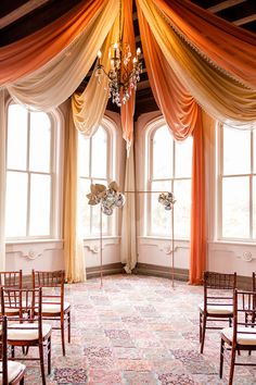 the room is decorated with orange drapes and chairs, along with chandeliers