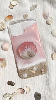 a cell phone case sitting on top of a white sheet covered in shells and sand