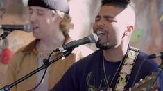 two young men singing into microphones while playing music