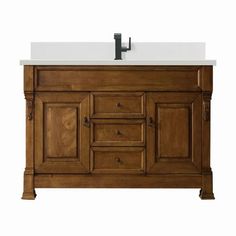 a bathroom vanity with a white counter top and wooden cabinet doors on both sides, along with a black faucet