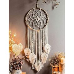 a decorative wall hanging with white feathers and hearts on the side, next to a potted plant