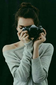 a woman holding up a camera to her face