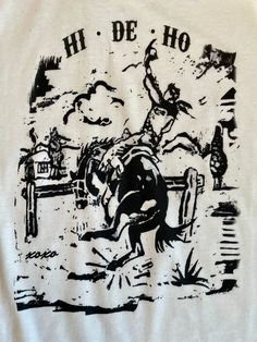 Capture the wild, untamed spirit of the West with this "Hi De Ho" Western Graphic Tee. This versatile white bronc tee looks great with your favorite jeans or styled with a skirt. "Hi De Ho" Western Graphic Tee Hand drawn and painted White Unisex Tee White Screen Print T-shirt For Rodeo, Western Graphic Tees, Country Western, White Painting, Favorite Jeans, The Wild, Graphic Tee, Looks Great, Hand Drawn