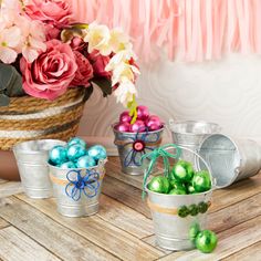 three buckets filled with colorful easter eggs on top of a wooden table next to flowers