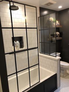 a bathroom with black and white tile walls, a toilet and bathtub in it