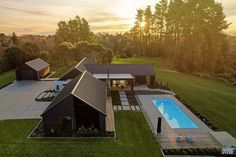 an aerial view of a house with a swimming pool in the foreground and trees on the other side