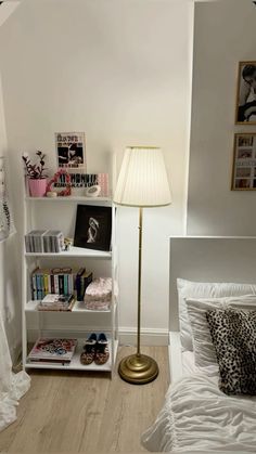 a bedroom with a bed, lamp and bookshelf on the floor in front of it