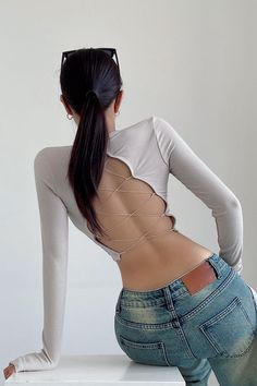 a woman with her back turned to the side, wearing jeans and a white top