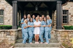 a group of women in matching blue pajamas posing for a photo on the front steps of a house