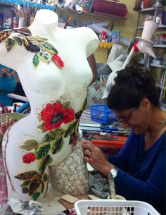 a woman is working on a statue in a room filled with craft supplies and other items