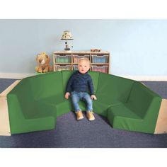 a baby sitting on top of a green couch