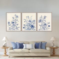 two blue and white flowers are hanging on the wall above a couch in a living room