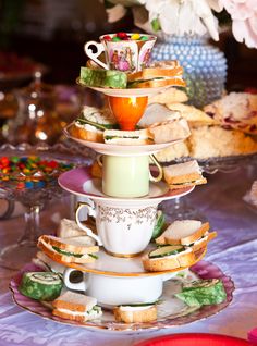 a stack of tea cups and sandwiches on a table