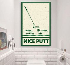 a toilet in a bathroom with a poster on the wall above it that says nice putt