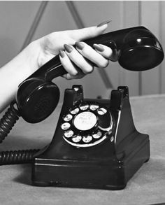 a woman's hand on an old fashioned telephone