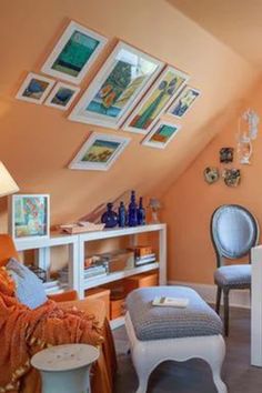 an attic bedroom with orange walls and pictures on the wall above the bed, along with two chairs