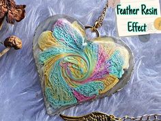 a heart shaped glass pendant with feathers on it and a note attached to the chain