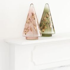 two glass vases sitting on top of a white mantle