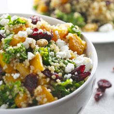 two white bowls filled with food sitting on top of a table next to cranberries