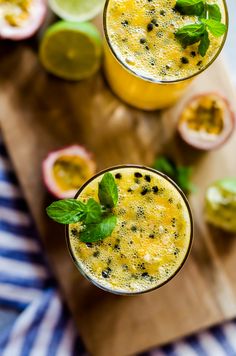 two glasses filled with orange juice and garnished with mint on a cutting board