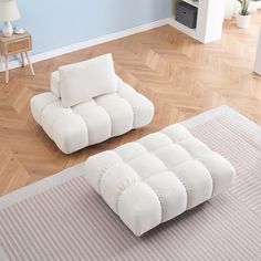 two white couches sitting on top of a hard wood floor next to a rug