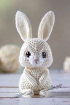 a white knitted bunny sitting on top of a wooden table