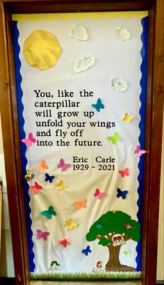 a bulletin board with an image of a tree and butterflies on it, in front of a quote from eric carl