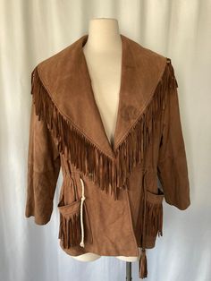 "Vintage 1980's 1990's women's brown leather coat with fringe on collar and pockets, drawstring waist, 2 snap button closure that overlaps, sewn in shoulder pads and bucket pockets on both sides and silky brown lining by Forenza Modern Classics Made in Korea Shell 100% Genuine Leather Lining 100% Nylon Good vintage condition with no rips but some stains on the collar and some minor scuffs throughout and drawstring on right side has been replaced Tag show size medium Measurements (laying flat): C Brown Winter Outerwear For Rodeo, Winter Leather Outerwear With Tassels, Winter Leather Tassel Outerwear, Brown Tasseled Outerwear For Spring, Vintage Leather Outerwear For Rodeo, Fall Leather Tassel Outerwear, Leather Tassel Outerwear For Fall, Brown Fringe Outerwear For Winter, Rodeo Outerwear With Tassels