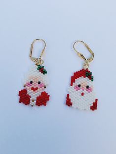 a pair of santa claus beaded earrings hanging from gold earwires on a white background