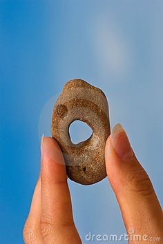 a hand holding a donut in front of a blue sky