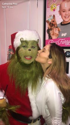 a woman kissing a man in a santa clause costume on the cheek while he is dressed up as an elf