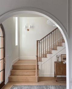 an arched doorway leads to a living room with hardwood floors and white walls, along with a gray area rug on the floor