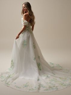 a woman in a white wedding dress with green flowers on the bouncy skirt