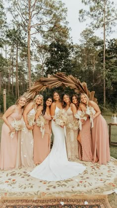 a group of women standing next to each other in front of a wooden arch with flowers on it