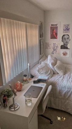 a bedroom with white bedding and pictures on the wall above it, along with a laptop computer