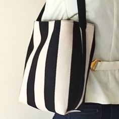 This is a versatile and stylish bag featuring eye-catching vertical stripes. The interior is fully lined and includes a convenient zippered pocket for your essentials. With a minimalist design, the bag closes simply with two drawstring ties, making it easy to access and perfect for any casual outing.  It also features a fixed, non-adjustable strap made of vegan leather. Perfect for moms on the go, it can be used as a top handle or shoulder bag. Great for everyday use or as a thoughtful gift for Striped Travel Bags With Adjustable Strap, Everyday Striped Shoulder Bag With Adjustable Strap, Striped Bag With Adjustable Strap For Everyday Use, Chic Travel Bag With Striped Lining, Everyday Striped Bag With Adjustable Strap, Striped Bag With Leather Handles For Everyday Use, Travel Shoulder Bag With Striped Lining, Travel Bags With Striped Lining, Everyday Striped Bags With Leather Handles