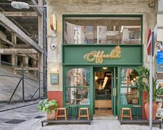 the entrance to an italian restaurant with green and gold lettering on the front door, along with two wooden chairs