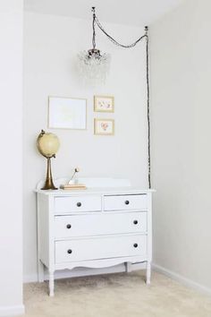 a white dresser sitting in a bedroom next to a wall with pictures hanging on it