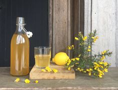 a bottle of lemonade next to a glass and some yellow flowers