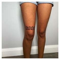 a woman's legs with the word 2000 written on them, in front of a white wall