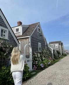 a woman walking down a gravel road next to houses